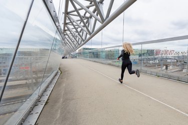 Woman runner during fast running exercise in modern city at cloudy day