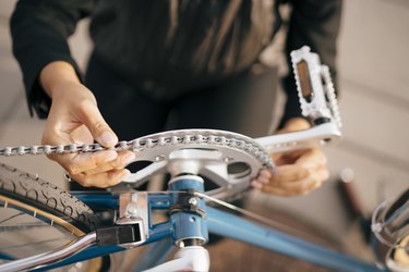 Midsection of businesswoman repairing bicycle in city