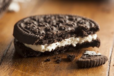 a close up of a chocolate sandwich cookie with cream filling on a wooden table