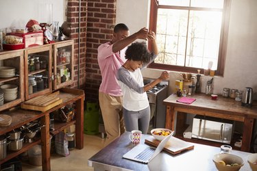 Mixed race couple dancing in kitchen, elevated view