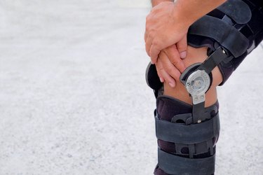 Cropped Image Of Man Wearing Knee Brace While Standing On Land