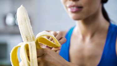 体育女人剥甜香蕉和糖尿病的零食,饿了之后积极锻炼在健身房