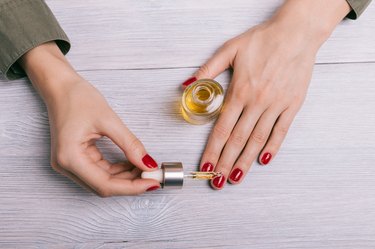 Female hand applied oil on the nails