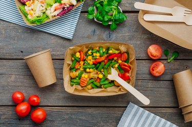 Steamed vegetables in the brown kraft paper food containers on wooden background