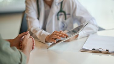 Doctor showing a patient some information on a digital tablet about effects of chemotherapy on the liver