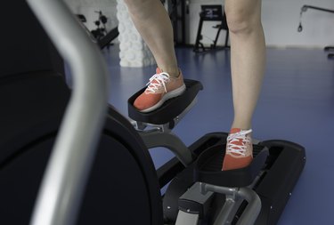 Woman's feet on cross-trainer at gym