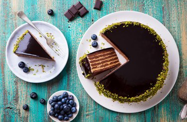 Chocolate cake on a white plate. Blue wooden background. Top view.