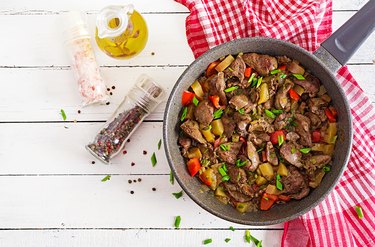 Fried chicken liver with apples and paprika in pan. Top view