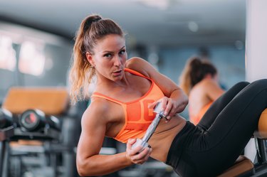 Female Athlete Doing Highly Effective Sit-Ups with Dumbbell