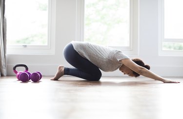 Woman warming up in child's pose for at-home crossfit 21-15-9 workout