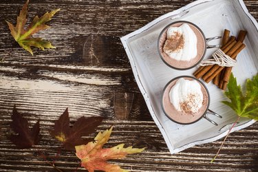 Homemade cinnamon and spice hot cocoa served with whipped cream. Thanksgiving table viewed from above