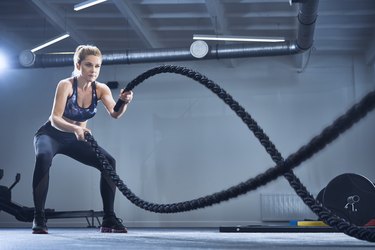 Athletic woman exercising with battle ropes at gym in increase creatinine and protein