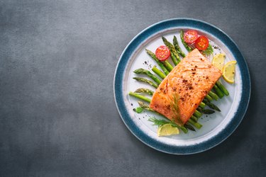 Grilled salmon garnished with green asparagus and tomatoes