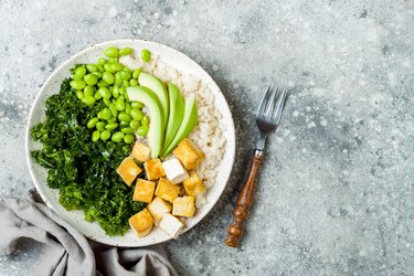 Cauliflower rice Buddha bowl with massaged kale, tofu, avocado and edamame beans. Vegan poke bowl