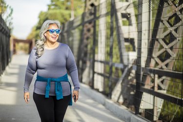 Mexican Woman Walking outside, smiling and wearing blue sunglasses