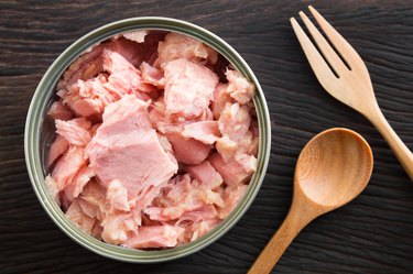 Canned soy free albacore white meat tuna packed in water on wood table background. Dark tone