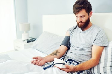 Young man checking blood pressure at home