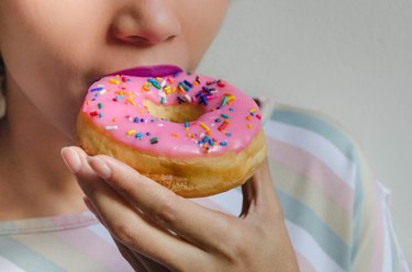 A woman eating a doughnut who has a sugar craving caused by gut problems