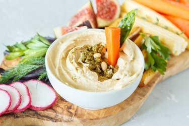 Hummus with vegetables and snacks on a wooden board