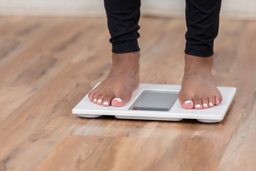 An unrecognizable woman stands on a bathroom scale