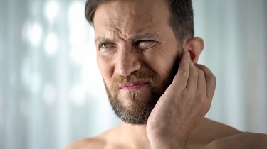 A man touching his ear because he has a bad smell behind his ears