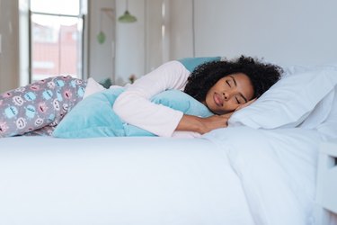 Happy beautiful young black woman lying down in the bed sleeping"n