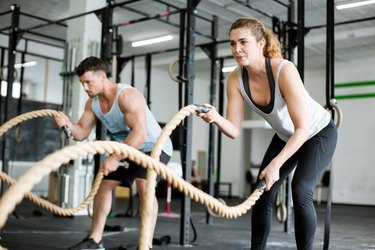 Fitness people working out with battle ropes