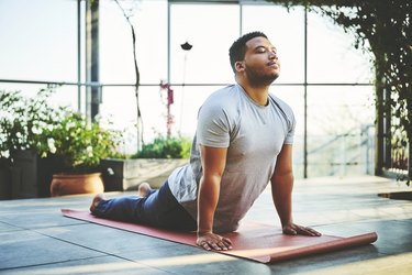 Person in gray T-shirt and navy blue sweatpants in upward-facing dog pose, practicing a 20-minute yoga flow for better mobility