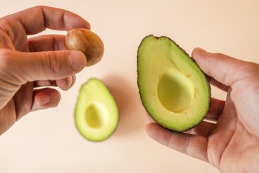 hands preparing avocado for eating.