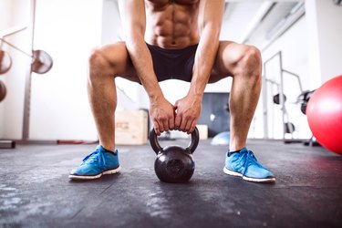 Unrecognizable fit hispanic man in gym working out with kettlebell