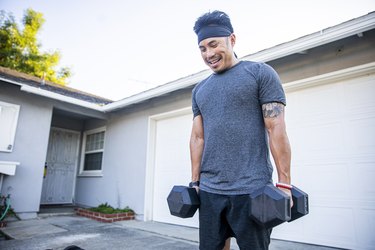 Filipino man working out with dumbbells outside to build muscle