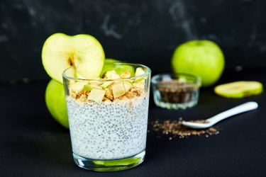 Healthy chia pudding with apples and granola in glass.