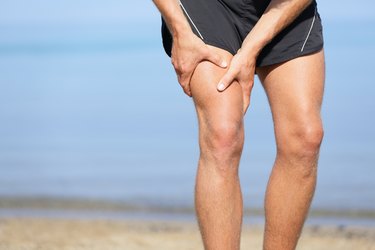 A waist-down view of a man holding his front thigh in pain