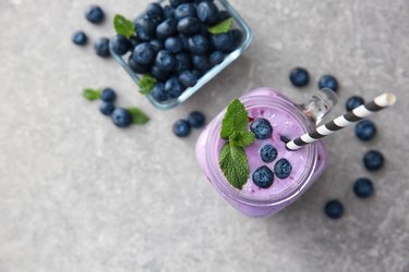 Mason jar of tasty blueberry smoothie on light table
