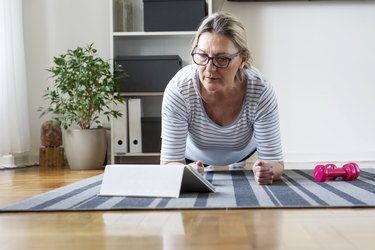 Senior woman following tutorial online and exercise at home during isolation for Covid - 19 at home