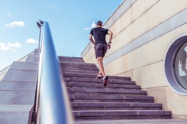 A male athlete runs in the morning jogging the steps, in the summer in the city sportswear t-shirt shorts sneakers, the background of the steps handrail, free space.