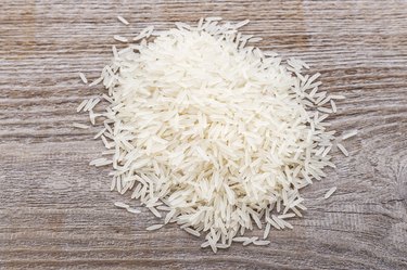 Basmati rice scattered on a wooden surface.
