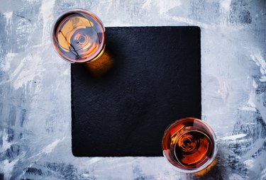 Cognac in two glasses on stone background, top view