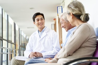 young asian doctor communicating with senior patient