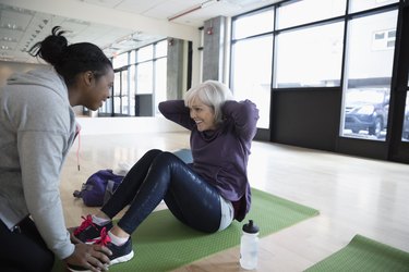 Personal trainer encouraging woman doing beginner HIIT workout at the gym
