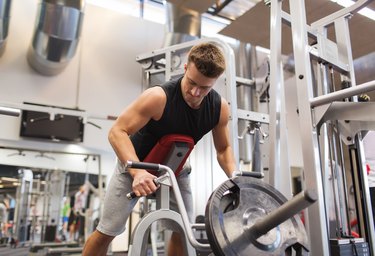 young man exercising on t-bar row machine in gym