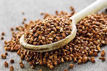 Wooden spoon overflowing with buckwheat grain