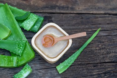 Fresh aloe vera stem and gel on wooden table, as a natural remedy for sunburns