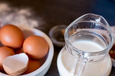 ingredients for making pancakes or cake - flour, egg, butter, milk on the old wooden background. top view. rustic or rural style.