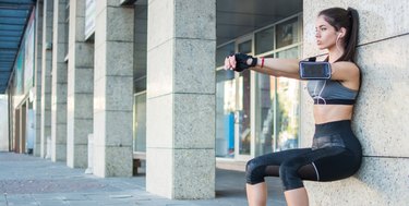 Young sporty girl doing wall sitting exercise urban outdoors.