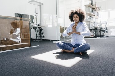 Young woman doing yoga in office