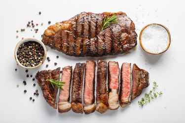 Two broiled marbled beef Delmonico steak with spices isolated on white background, top view