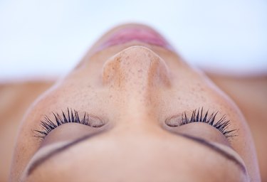 A woman with freckles, sleeping or meditating.