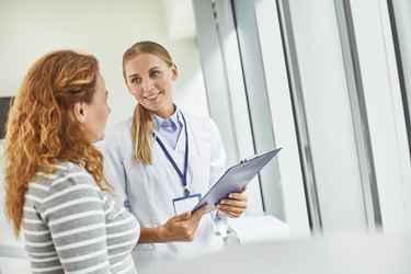 Young doctor holding clipboard while looking at patient