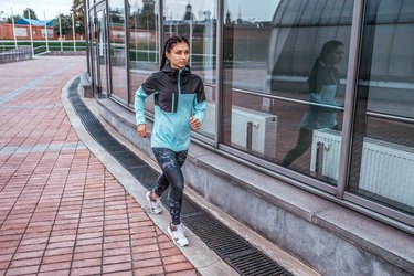 Woman athlete girl runs in the city in autumn in spring, fitness workout, motivation is power. Active lifestyle. Sportswear, free space, achievement, success, endurance competition.